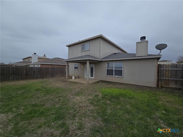 rear view of property with a fenced backyard, a chimney, a patio, and a yard