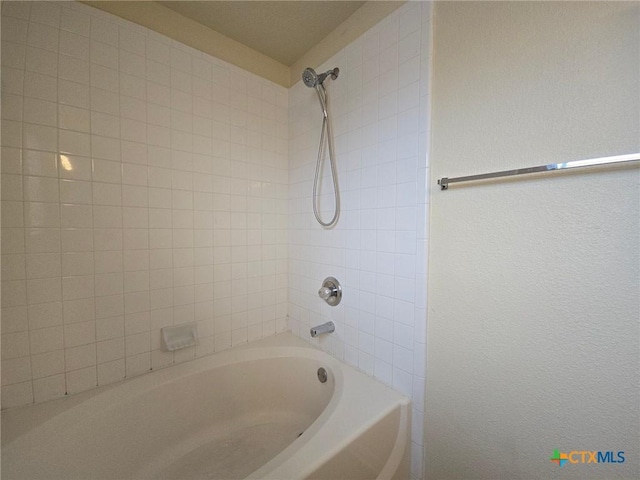 bathroom featuring a textured wall and bathtub / shower combination