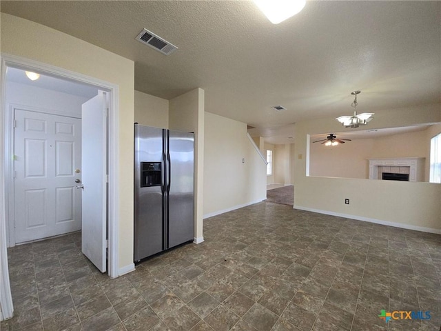 kitchen with ceiling fan, a fireplace, visible vents, open floor plan, and stainless steel fridge