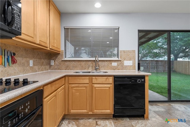 kitchen featuring a sink, stone finish floor, backsplash, and black appliances