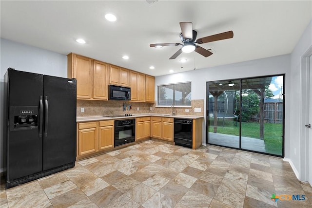 kitchen featuring ceiling fan, light countertops, stone finish flooring, backsplash, and black appliances