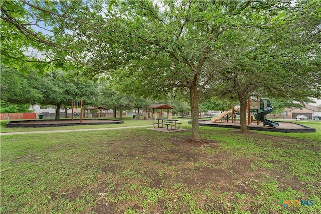 view of community featuring a lawn, fence, and playground community