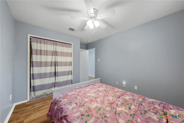 bedroom featuring visible vents, baseboards, ceiling fan, and wood finished floors