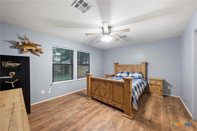 bedroom with baseboards, ceiling fan, light wood finished floors, and visible vents