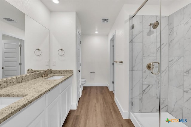 bathroom featuring wood-type flooring, vanity, toilet, and a shower with shower door