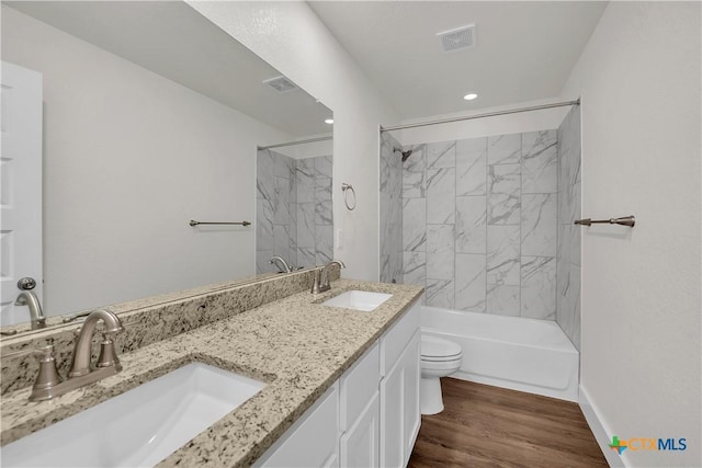 full bathroom featuring tiled shower / bath, hardwood / wood-style floors, vanity, and toilet