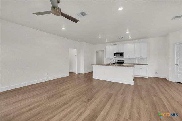 kitchen featuring a kitchen island with sink, sink, light wood-type flooring, appliances with stainless steel finishes, and white cabinetry