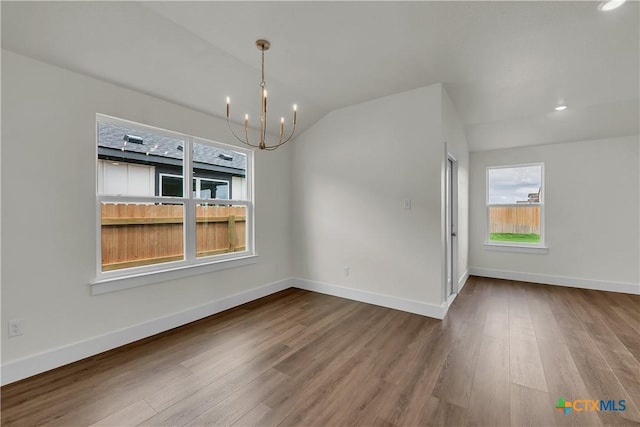 unfurnished dining area with a notable chandelier, wood-type flooring, and vaulted ceiling