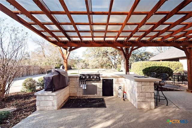 view of patio / terrace featuring grilling area, fence, an outdoor kitchen, and a pergola