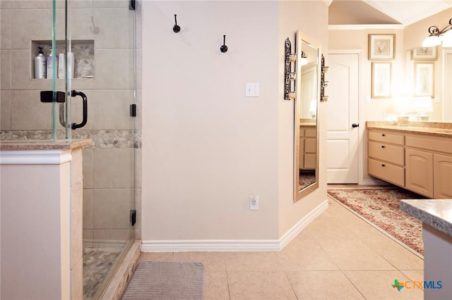 bathroom with baseboards, a stall shower, vanity, and tile patterned flooring