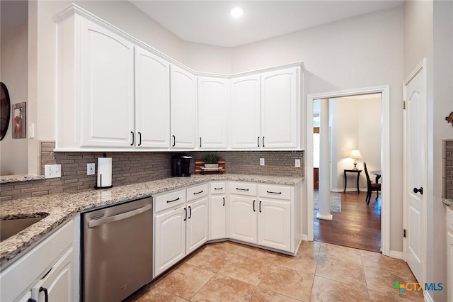 kitchen featuring decorative backsplash, light stone countertops, stainless steel dishwasher, and white cabinets