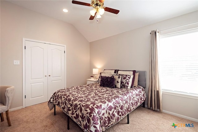 carpeted bedroom with a closet, lofted ceiling, baseboards, and a ceiling fan