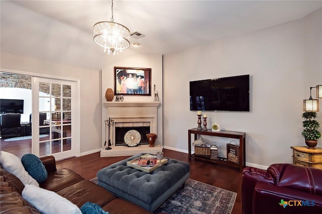 living room with visible vents, a fireplace with raised hearth, baseboards, and wood finished floors