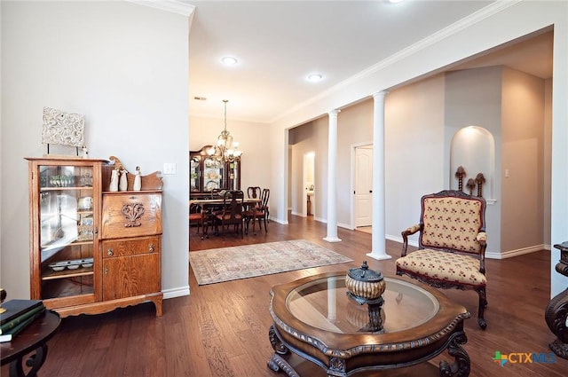 sitting room featuring wood finished floors, baseboards, ornate columns, ornamental molding, and a notable chandelier