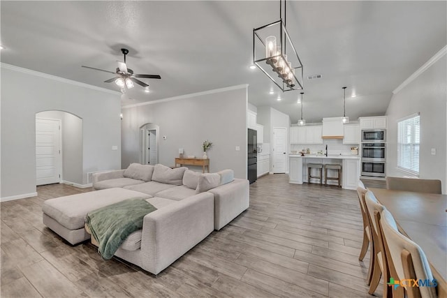 7611 Iridium Dr, Killeen, TX 76542 - living area featuring arched walkways, a ceiling fan, crown molding, light wood finished floors, and baseboards