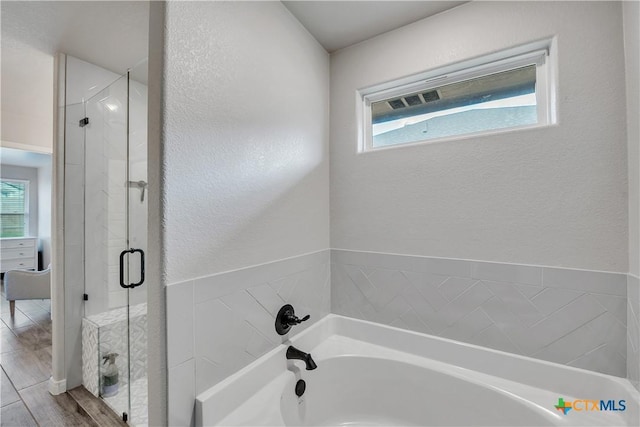 7611 Iridium Dr, Killeen, TX 76542 - bathroom with a garden tub, a shower stall, plenty of natural light, a textured wall, and wood finished floors