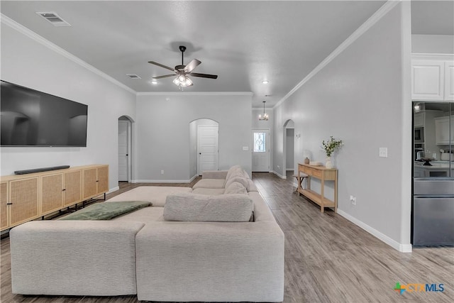 7611 Iridium Dr, Killeen, TX 76542 - living room featuring arched walkways, ceiling fan, light wood-type flooring, crown molding, and baseboards