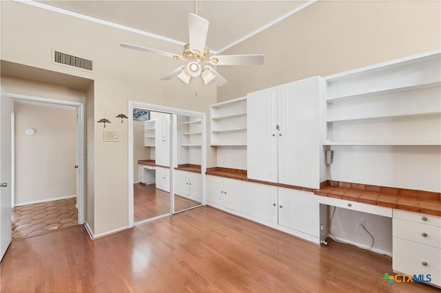 667 Fredericksburg Rd, New Braunfels, TX 78130 - unfurnished bedroom featuring visible vents, a ceiling fan, wood finished floors, baseboards, and built in study area