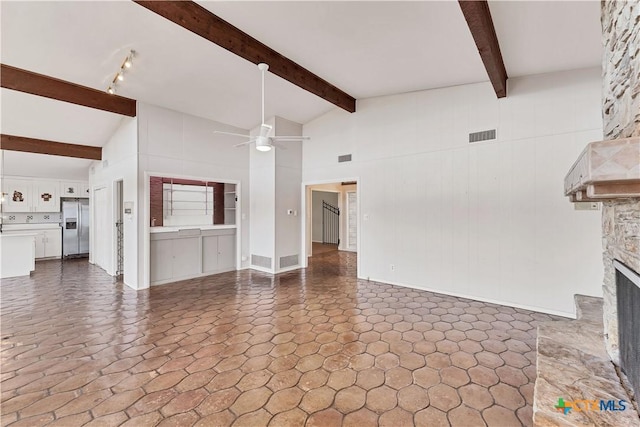 667 Fredericksburg Rd, New Braunfels, TX 78130 - unfurnished living room with visible vents, beam ceiling, a fireplace, and a ceiling fan