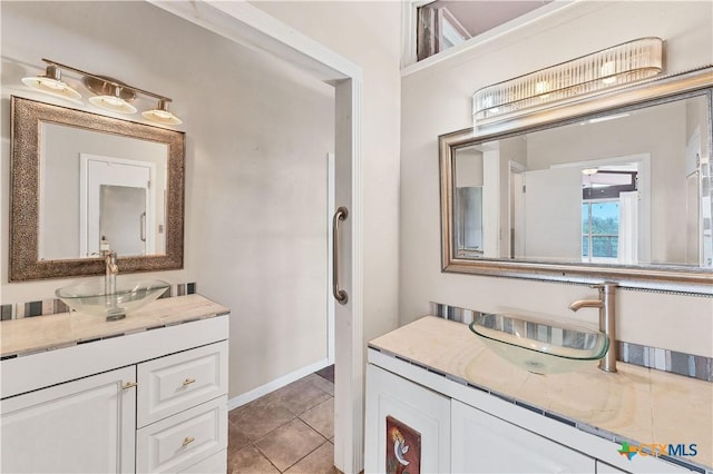 667 Fredericksburg Rd, New Braunfels, TX 78130 - bathroom featuring tile patterned floors, two vanities, baseboards, and a sink