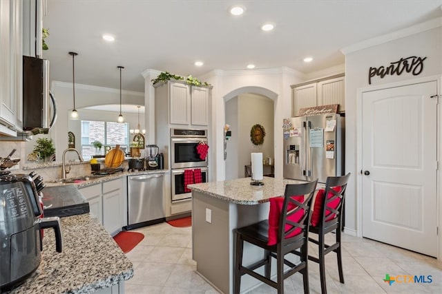 kitchen featuring a kitchen island, sink, decorative light fixtures, and stainless steel appliances