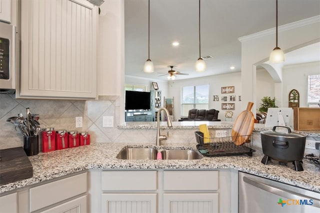 kitchen featuring hanging light fixtures, sink, tasteful backsplash, ceiling fan, and crown molding