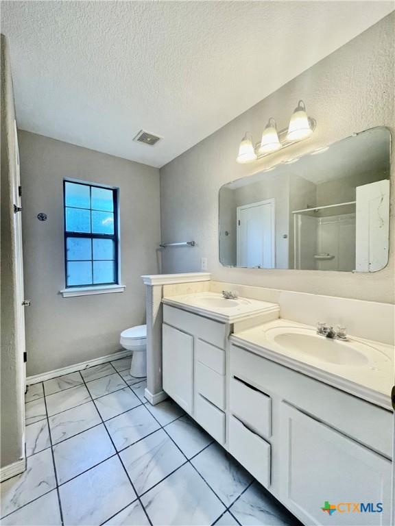 1715 Ramona Cir, San Marcos, TX 78666 - full bath featuring double vanity, a shower stall, marble look tiles, and a textured ceiling