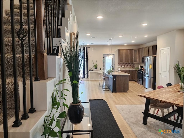 kitchen featuring a kitchen bar, sink, hanging light fixtures, a kitchen island, and stainless steel appliances