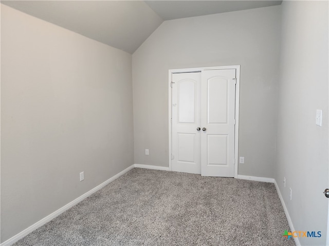 unfurnished room with carpet floors and vaulted ceiling