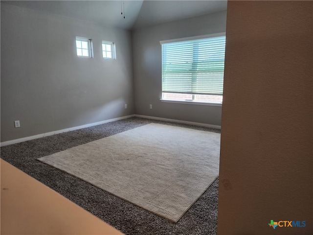 carpeted empty room featuring vaulted ceiling