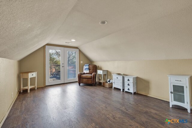 additional living space with vaulted ceiling, dark wood-type flooring, a textured ceiling, and french doors