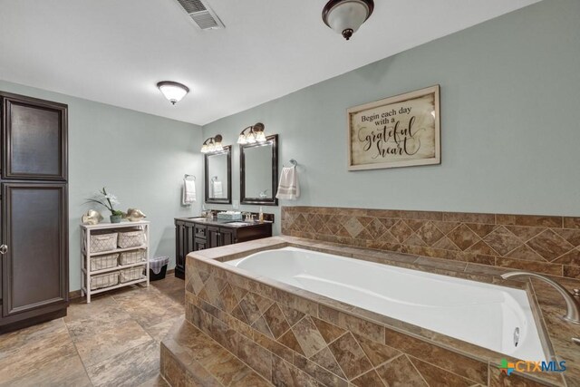 bathroom with vanity and tiled bath