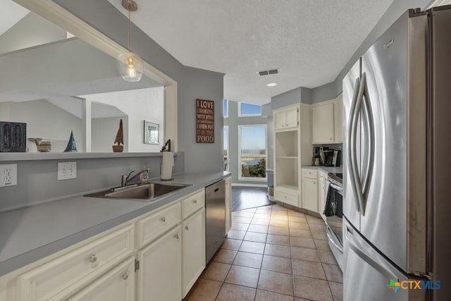 kitchen with sink, appliances with stainless steel finishes, a textured ceiling, light tile patterned flooring, and decorative light fixtures