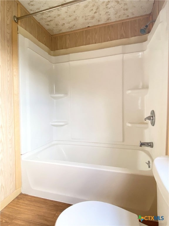 bathroom featuring bathtub / shower combination, hardwood / wood-style floors, and toilet