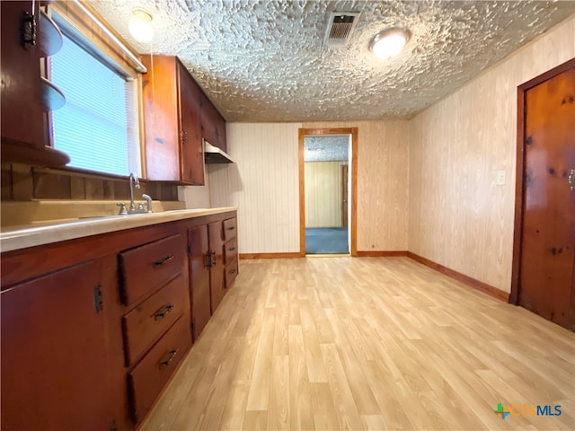 kitchen with a textured ceiling, light hardwood / wood-style flooring, and sink