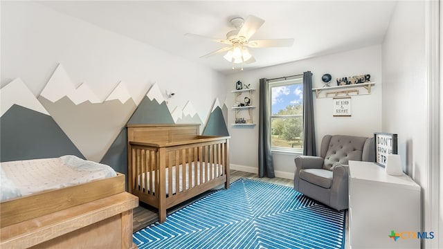 bedroom featuring hardwood / wood-style flooring, ceiling fan, and a nursery area