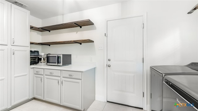 kitchen with washing machine and dryer, light tile patterned floors, and white cabinets