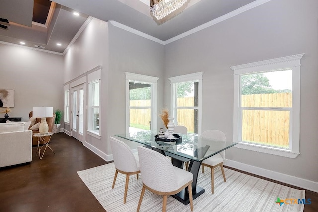 dining room with an inviting chandelier, a towering ceiling, ornamental molding, and a healthy amount of sunlight