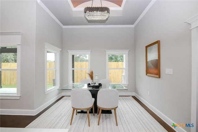 dining room with an inviting chandelier, a healthy amount of sunlight, ornamental molding, and dark hardwood / wood-style floors