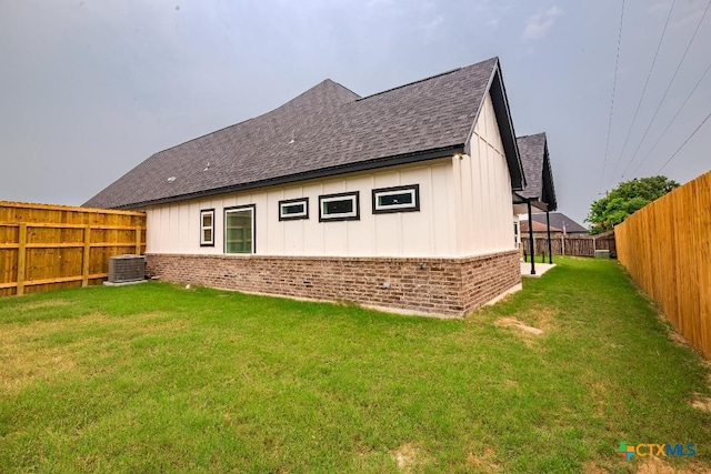 rear view of property featuring a yard and cooling unit