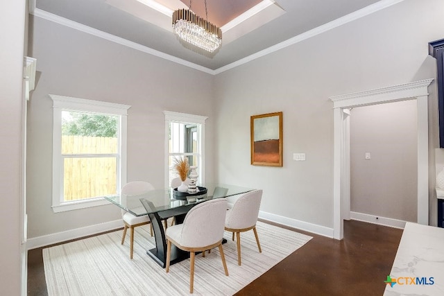 dining area featuring a notable chandelier, a towering ceiling, ornamental molding, and a raised ceiling