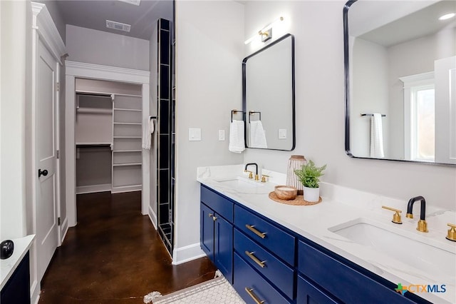 full bathroom with concrete flooring, a walk in closet, double vanity, and baseboards