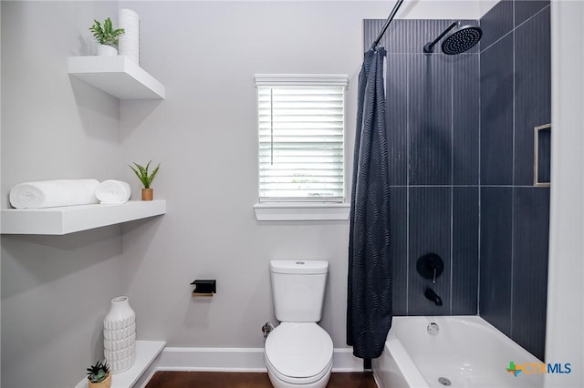 full bath featuring toilet, shower / bath combo with shower curtain, and baseboards