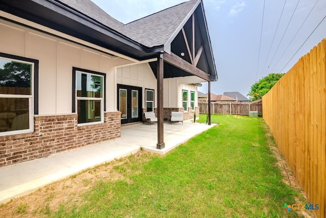 rear view of property with a shingled roof, brick siding, board and batten siding, and a patio area