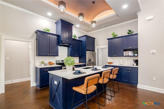 kitchen featuring crown molding, a breakfast bar, appliances with stainless steel finishes, a tray ceiling, and an island with sink