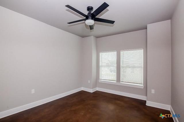 spare room featuring finished concrete floors, baseboards, and a ceiling fan