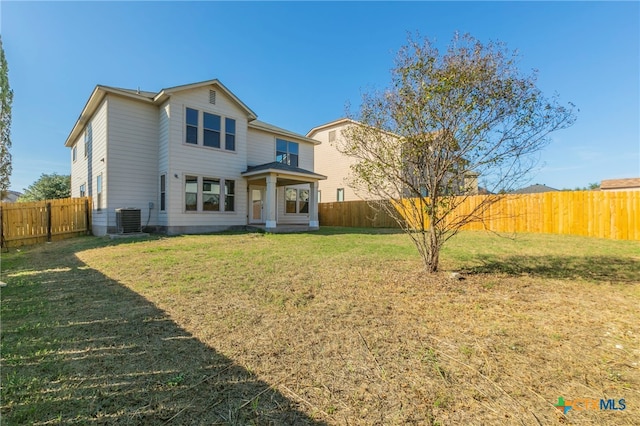 rear view of property with cooling unit and a yard