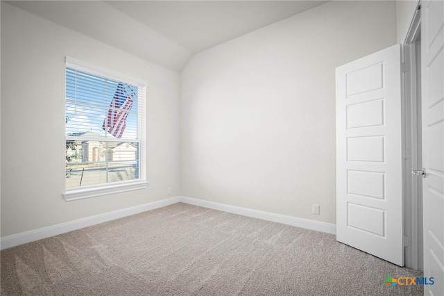 spare room featuring carpet and lofted ceiling