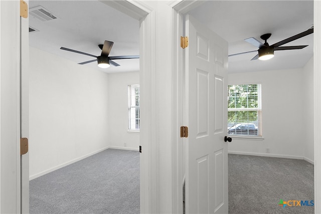 carpeted spare room with a wealth of natural light and ceiling fan