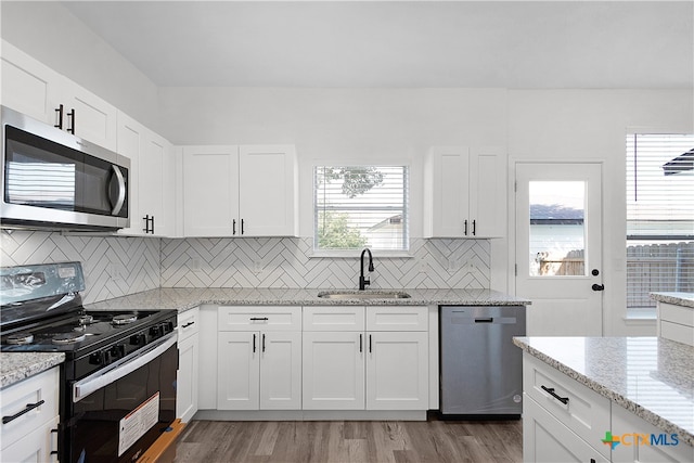 kitchen with a healthy amount of sunlight, light hardwood / wood-style flooring, sink, white cabinetry, and appliances with stainless steel finishes